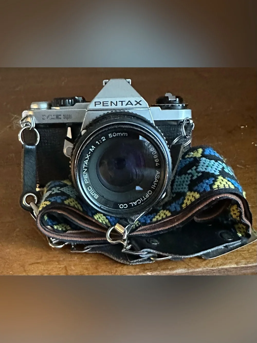 Pentax Silver and Black SLR Camera with Black Lens Cap and Colorful Strap
